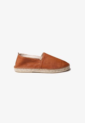 Zapato marrón de cuero sin cordones con punta redondeada, suela de yute trenzado y costura a lo largo del borde. Textura suave, diseño minimalista.