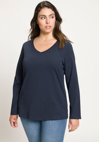 Námořnická modrá halenka s dlouhým rukávem a výstřihem do V z měkkého materiálu, s uvolněným střihem, která má čistý a jednoduchý design bez viditelných vzorů nebo akcentů.