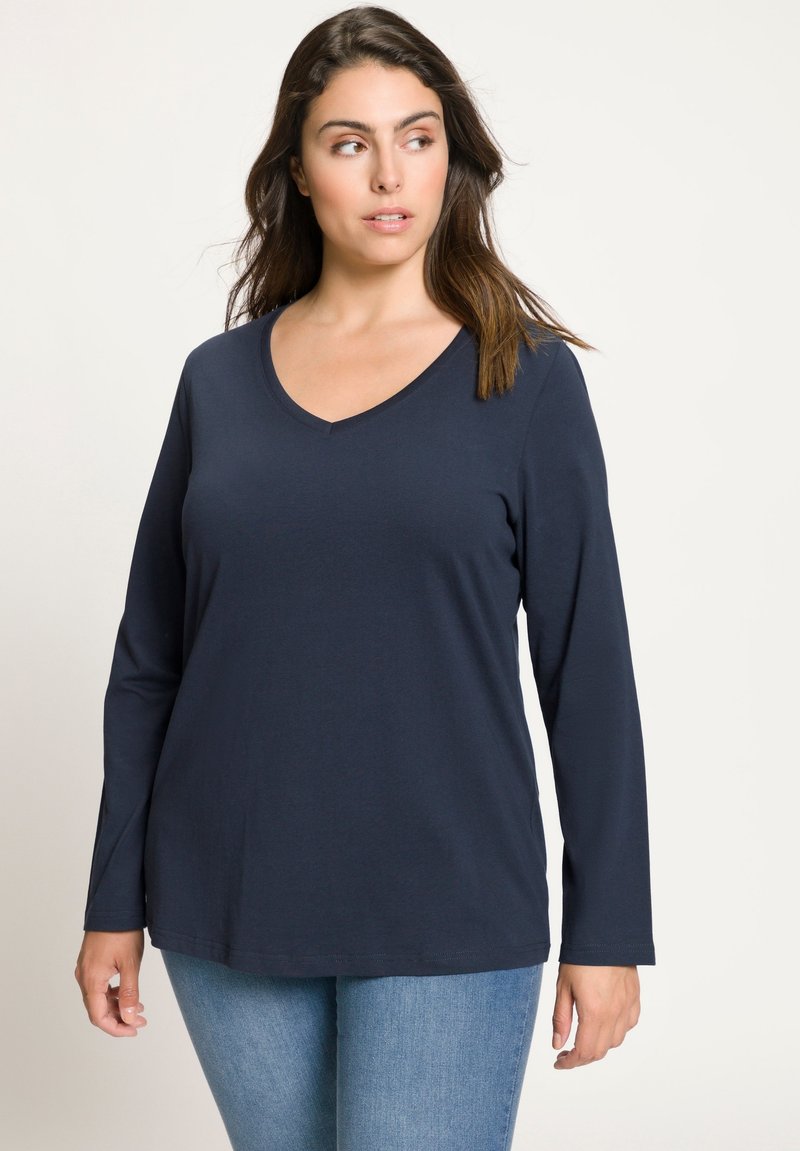 Námořnická modrá halenka s dlouhým rukávem a výstřihem do V z měkkého materiálu, s uvolněným střihem, která má čistý a jednoduchý design bez viditelných vzorů nebo akcentů.