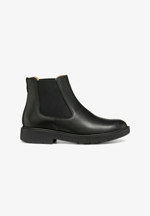 Botte Chelsea en cuir noir avec des panneaux latéraux élastiques et une semelle basse et épaisse, vue de l'extérieur sur fond blanc.