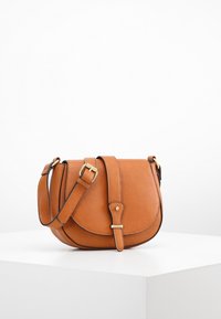 Brązowa skórzana torebka typu crossbody z zaokrągloną klapką, regulowanym paskiem, złotymi akcesoriami i gładką fakturą. Kompaktowy i minimalistyczny design.