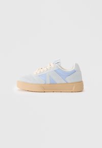 Lys blå og blek grå semsket sneakers med beige såle. Har en glatt finish, rund form, og kremfargede snørebånd. Teksturerte detaljer synlige.