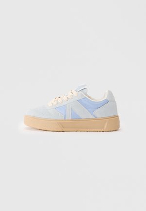 Sneaker in suede azzurro chiaro e grigio pallido con suola beige. Presenta una finitura liscia, forma arrotondata e lacci crema. Accenti testurizzati visibili.