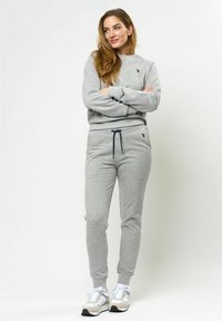 Grijze sweatshirt en jogger set, gemaakt van zacht materiaal. De sweatshirt heeft een ronde hals, de broek heeft elastische boorden en een verstelbare trekkoord.