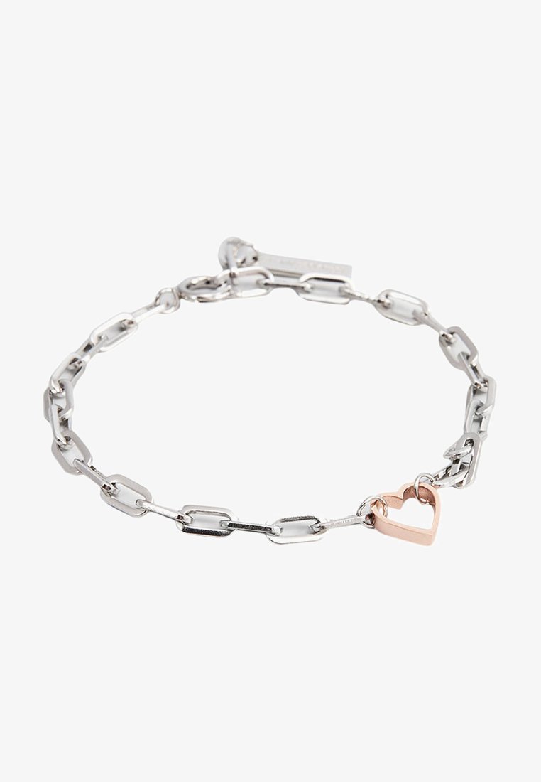 Silberne Kettenarmband mit elongated Gliedern und einem kleinen Herzanhänger aus Roségold. Glatte Textur mit polierter Oberfläche.
