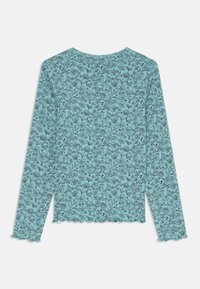 Μακρυμάνικο μπλουζάκι σε ανοιχτό μπλε ύφασμα με λουλουδάτο μοτίβο σε μαύρο, με φινίρισμα σε λοξό τελείωμα και στρογγυλή λαιμόκοψη. Όψη από πίσω.