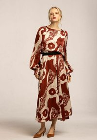 Lång, flödande klänning med ett röd och krämfärgat blommönster, med ett åtsittande svart midjeband och puffärmar. Slät tygtextur.