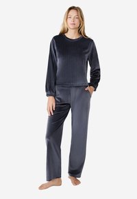 Donkergrijs velours loungewear set bestaande uit twee delen. Langsleeve top met een ronde halslijn, bijpassende relaxte broek met zijzakken.