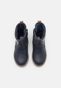 Marineblaue Lederstiefel knöchelhoch mit Kunstfellfutter, seitlichen Reißverschlüssen und einem strukturierten Roségold-Detail auf der Rückseite. Rutschfeste Gummisohlen.