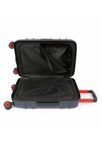 Tvrdý kufr v tmavě šedé barvě s červenými koly a rukojetí. Obsahuje vnitřní zipovou kapsu a černou podšívku. Kompaktní design s robustní konstrukcí.