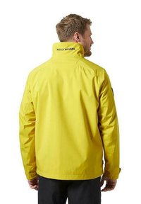 Giacca impermeabile gialla con colletto alto, dotata del logo Helly Hansen sul collo, texture liscia e maniche lunghe.