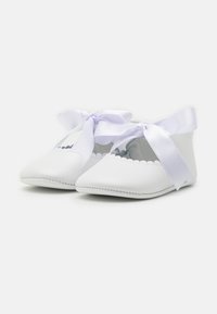Weiße Lederschuhe mit spitzen Zehen, gewellten Kanten und breiten lavendelfarbenen Satinbändern zum Binden. Sichtbare Nähte entlang der Sohle.