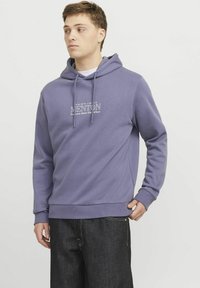 Sudadera morada con capucha ajustable, bolsillo canguro en la parte frontal y un diseño de texto impreso. Material suave y puños y dobladillo acanalados.