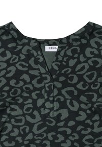 Haut en imprimé léopard noir et vert avec un design en V, fabriqué à partir d'un tissu doux. Présente une étiquette "CECIL" près du col.