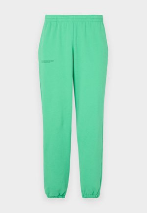 Green sweatpants made of soft fabric, featuring an elastic waistband and cuffs, with minimalist text printed on the outer thigh.