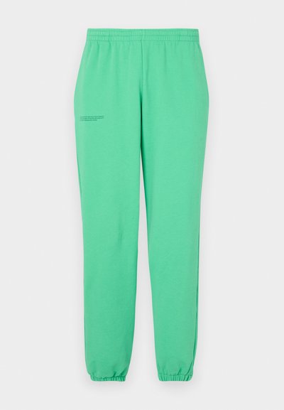 Zelene trenirke iz mehkega materiala, z elastičnim pasom in manšetami, s minimalističnim besedilom, natisnjenim na zunanji strani stegnenice.