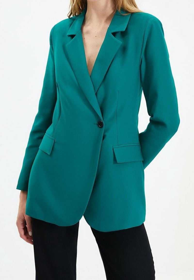 Blazer bleu sarcelle à coupe ajustée, col à revers crantés, fermeture à un bouton et deux poches avant. Tissu lisse avec une finition élégante.