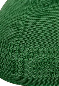Green knitted cap featuring a textured pattern, smooth edges, and a subtle ribbed design. The material appears lightweight and breathable.