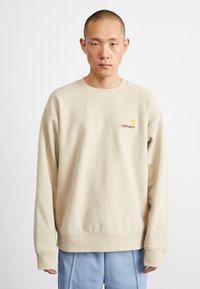 Beige sweatshirt met een ronde hals, ribgebreide mouwen en zoom. Bevat een klein rood logo op de borst. Smooth katoenstof.