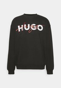 Sudadera negra con un logo gráfico blanco y rojo "HUGO" en el frente. Puños y cuello acanalados, material de algodón suave.