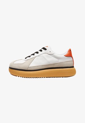 Sneaker bianca con dettagli in suede, lacci neri e un tallone arancione testurizzato. Presenta una suola in gomma spessa e tranciata. Design pulito e minimalista.