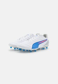 Scarpini da calcio bianchi con accenti blu, dotati di una superficie texturizzata, design con lacci e numerosi tacchetti blu sulla suola per una migliore aderenza.