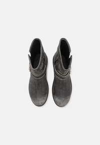 Botas negras hasta el tobillo con una superficie ligeramente desgastada, que cuentan con una cremallera en el lateral y un diseño de punta redonda. Tejido texturizado con un acabado suave.