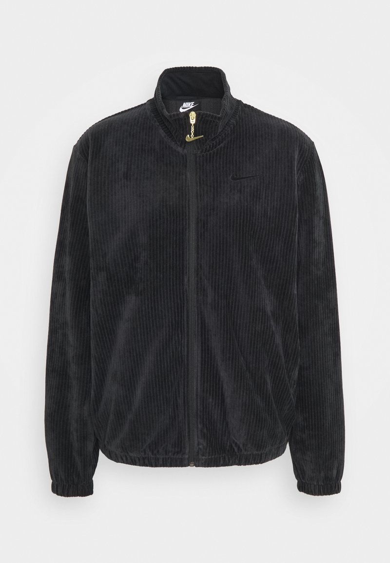 Černá kordurová bunda s vysokým límcem, zipem a elastickými manžetami. Na hrudi je decentní logo Nike a kontrastní zlaté kovové prvky.