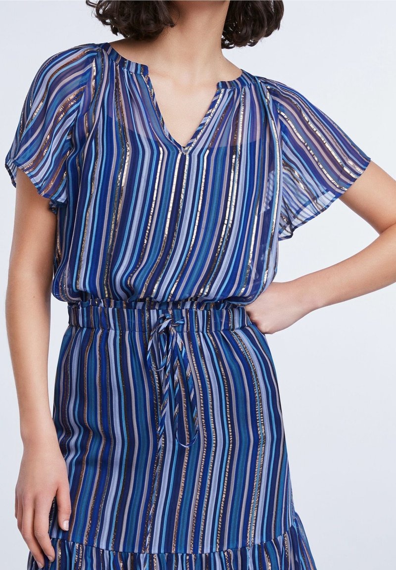 Blau- und lila gestreiftes Kleid aus transparenter Stoff, mit kurzen, flatternden Ärmeln, V-Ausschnitt und einer Bindegürtel. Verfügt über metallische Akzente im gesamten Kleid.