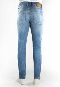 Lichtblauwe denim jeans met een slim fit, voorzien van twee achterzakken en een tan leren label op de tailleband. Gestructureerde stof met vervaging.