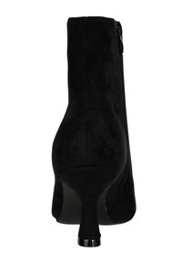 Botín de ante negro con tacón curvado y cierre de cremallera. Presenta una textura suave y un diseño elegante, adecuado para diversos atuendos.