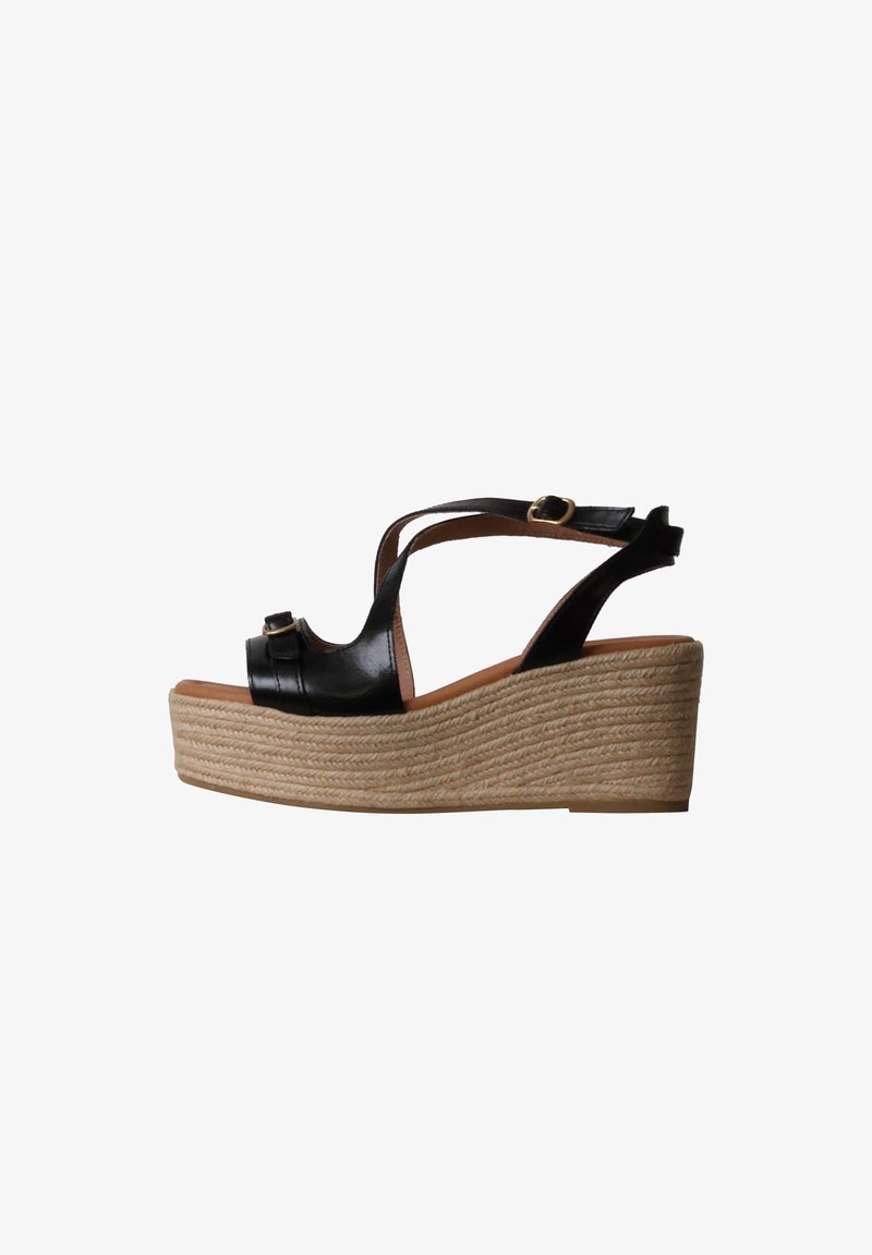 Sandale compensée en cuir noir avec bride à la cheville, boucle latérale et semelle plateforme épaisse et texturée.