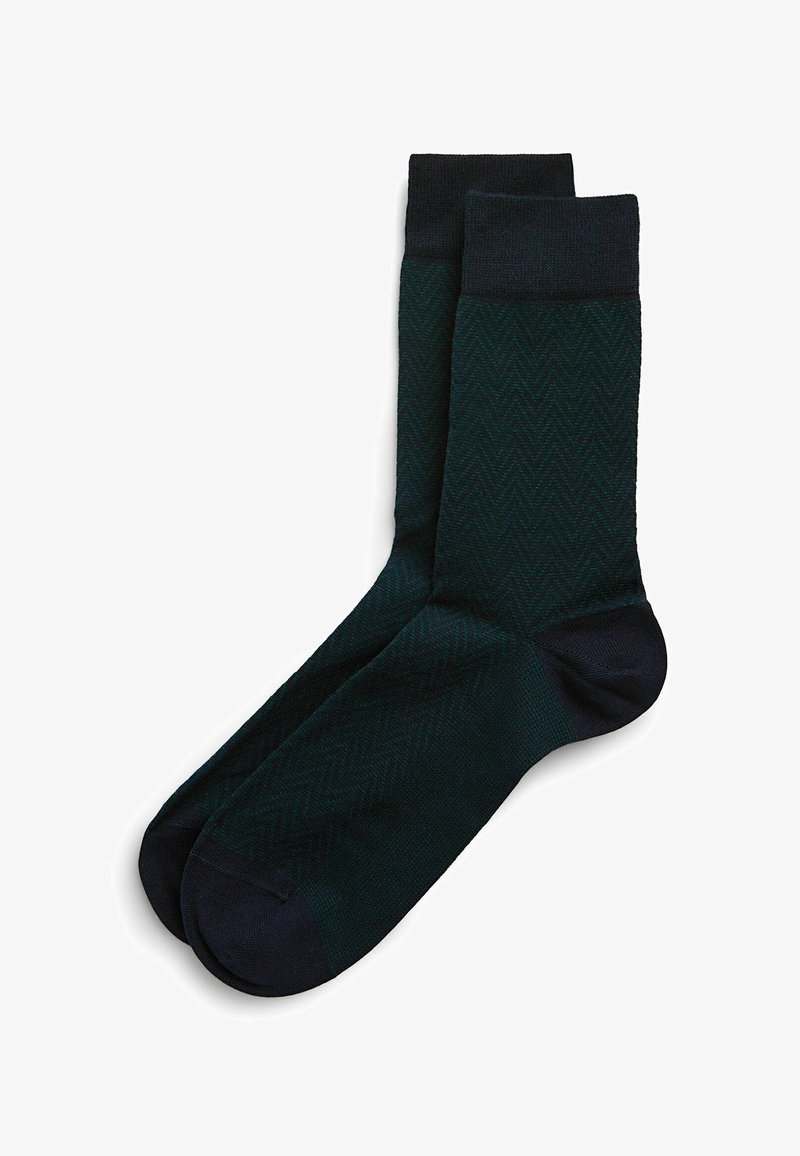 Mørkegrønne sokker med et fiskebensmønster, der har en ensfarvet marineblå manchet og tå. Lavet af tekstureret materiale for komfort.