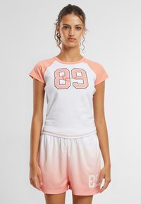 Set sportiv alb și roz deschis, format dintr-un top cu mânecă scurtă, având un grafic "89", și pantaloni scurți ombre asortați. Material moale, croială confortabilă.
