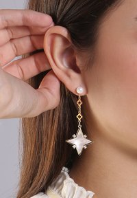 Goldene hängende Ohrringe mit einem Perlenstecker, einem sternförmigen Akzent aus Perlmutt und kleinen klaren Kristallverzierungen.