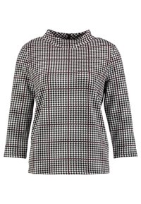 Top a maniche lunghe in bianco e nero con motivo houndstooth, colletto alto e linee a griglia di colore rosso scuro.