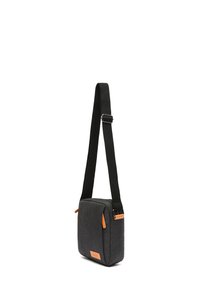 Sivi platneni crossbody kofer kvadratnog oblika, s crnom podesivom trakom i svijetlosmešavim kožnim detaljima. Ima zatvaranje na patentni zatvarač i prednju džep.