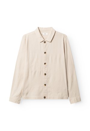 Camisa beige claro de manga larga con botones y cuello, con seis botones oscuros al frente y un sutil bolsillo en el pecho del lado izquierdo.