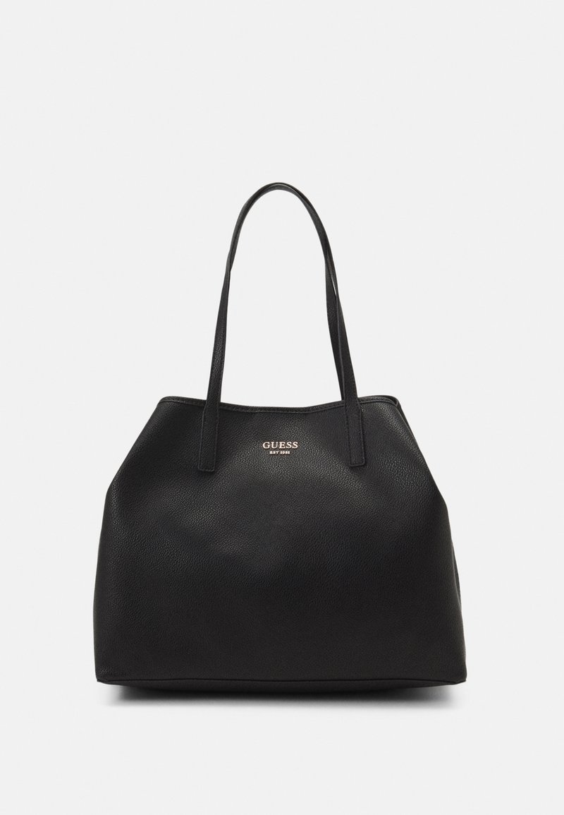 Black faux leather tote bag with two long handles, rounded shape, textured surface, and a gold logo on the front.