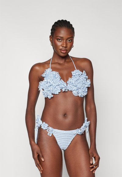 Bikini croșetat de culoare albastru deschis, cu accente florale pe top și laterale, cu brățări la gât și detalii texturate pe întreaga suprafață.