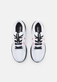 Bijele mrežaste tenisice za trčanje s crnim vezicama i akcentima, s crvenim swoosh logom. Udoban đon s teksturiranim gornjim dijelom za prozračnost.