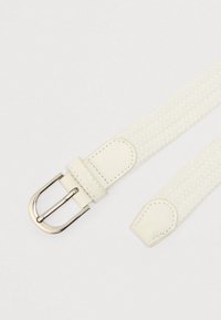 Hvid flettet bælte med spænde i metal, der har læderdetaljer ved spænde og spids, med et tekstureret design og ren syning.