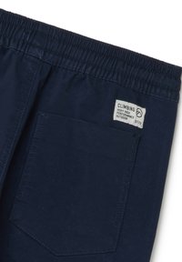 Marineblauwe klimsp trousers met een elastische tailleband, voorzien van een rechthoekig label en een enkele achterzak met een scherpe hoek.