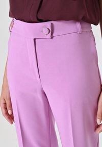  Lichtroze op maat gemaakte broek met een gladde textuur, voorzien van een platte voorkant, riemlussen en een zilveren cirkelvormige knoopaccent.