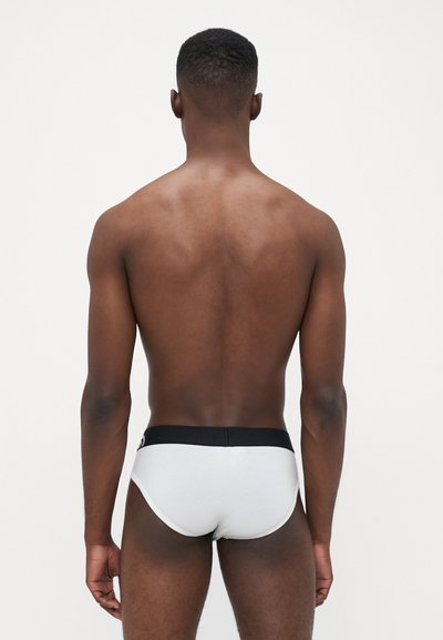 Herren weiße Slips mit einem schwarzen elastischen Bund, die eine glatte Baumwolltextur und eine abgerundete Form zeigen, von hinten betrachtet.