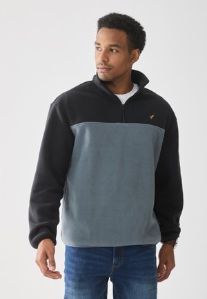 Fleece pullover in lichtblauw en zwart. Ritskraag, lange mouwen, textuurstof, met een klein gouden logo op de borst. Casual pasvorm.