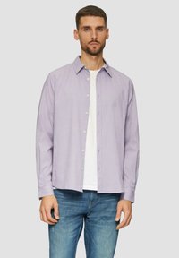 Jasnofioletowa koszula w kratę z guzikami, z kołnierzykiem, długimi rękawami i luźnym krojem, noszona na białym t-shircie, połączona z niebieskimi dżinsami.