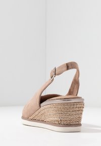 Beige suède wedge sandaal met een slingback bandje, een tekstuur geweven espadrille tussenzool en een gladde zool. Zilveren hardware accent op het bandje.