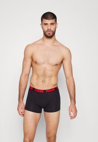 Boxers ajustados negros con un logotipo "PUMA" rojo en contraste en la cinturilla, fabricados con un material suave y flexible, que ofrecen un ajuste ceñido.