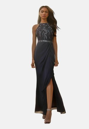 Black evening gown with halter neck, jeweled bodice, side slit, and draped fabric. Features beaded detailing and a fitted waistline.